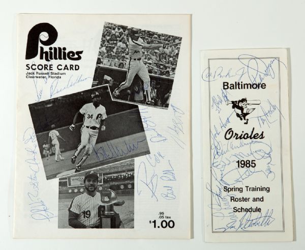 1983 PHILADELPHIA PHILLIES SPRING TRAINING SCORECARD SIGNED BY 11 AND 1985 BALTIMORE ORIOLES TEAM SIGNED SPRING TRAINING ROSTER SIGNED BY 12
